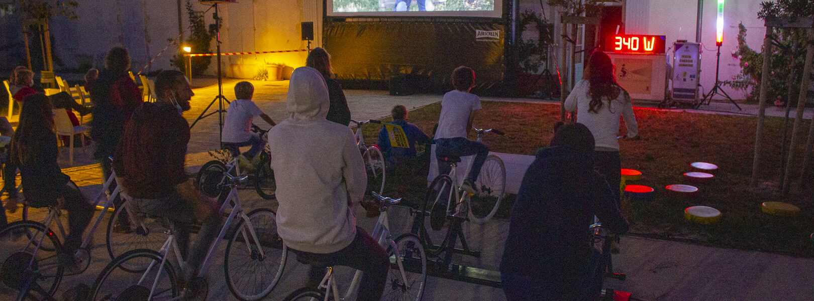 Montage du dispositif Vélo Cinéma de Ludik Énergie, montrant des vélos générateurs connectés à un écran gonflable et à un système de sonorisation en plein air.