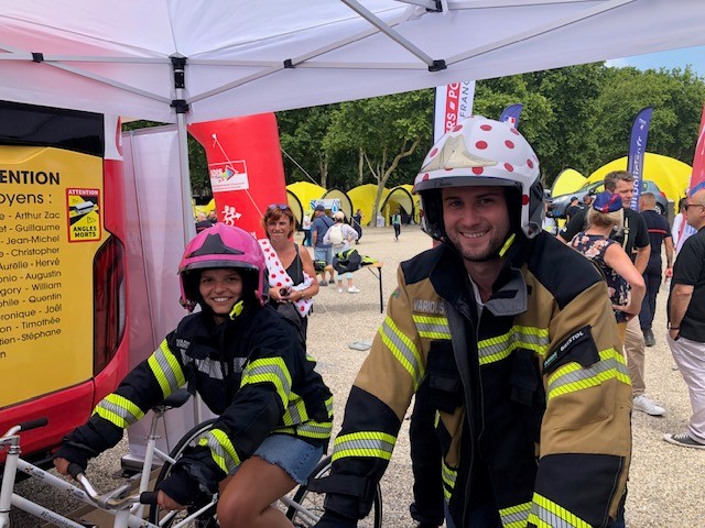 Un père et sa fille, sur l’animation Vélo Battle du roadshow Tour de France, déguisés en pompiers avec le casque et la veste