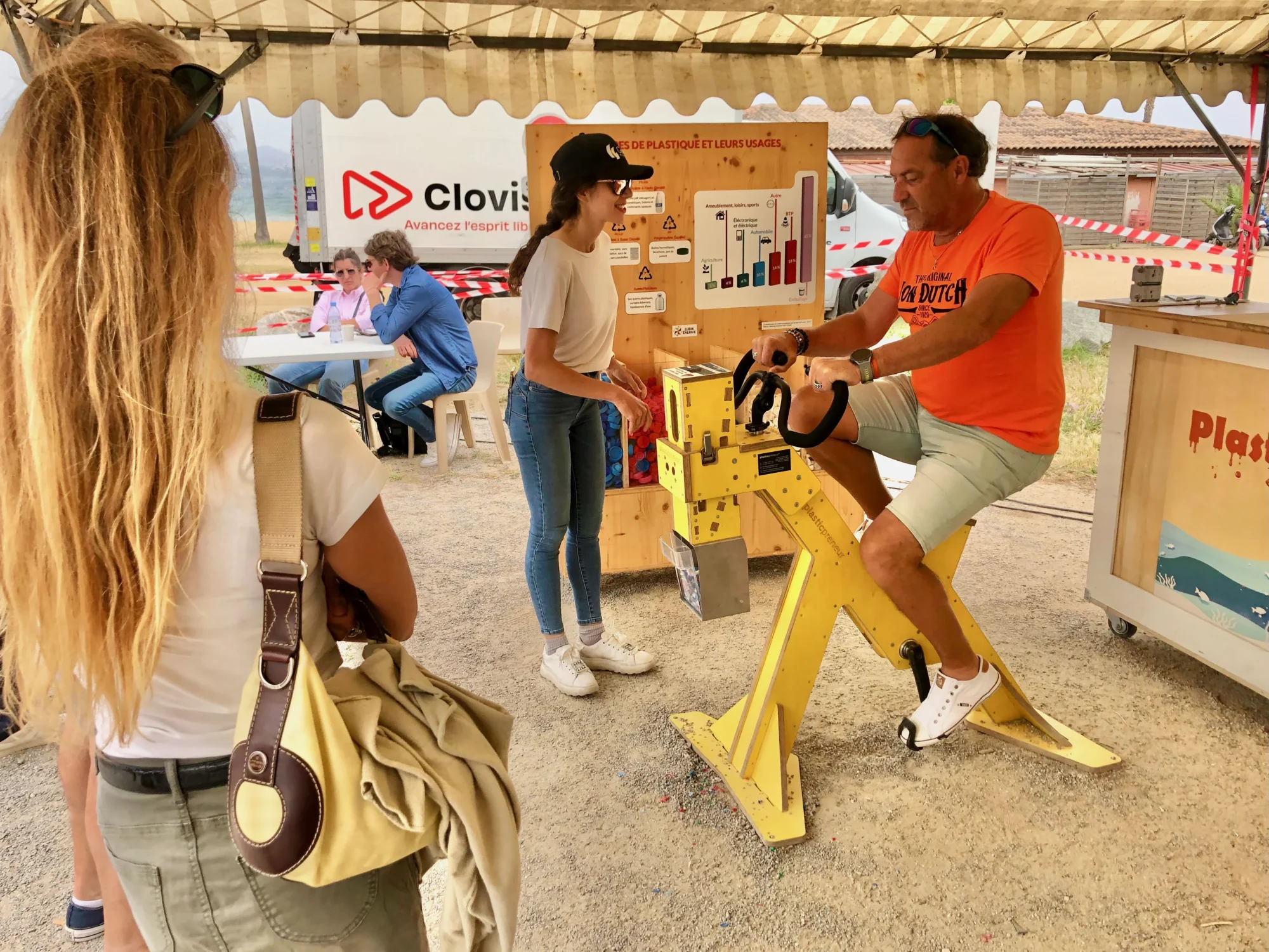 Un participant pédale sur l’animation Plasticycle, pour créer un goodie en plastique recyclé avec une animatrice qui fait de la sensibilisation environnementale, à l’occasion d’un team building green.